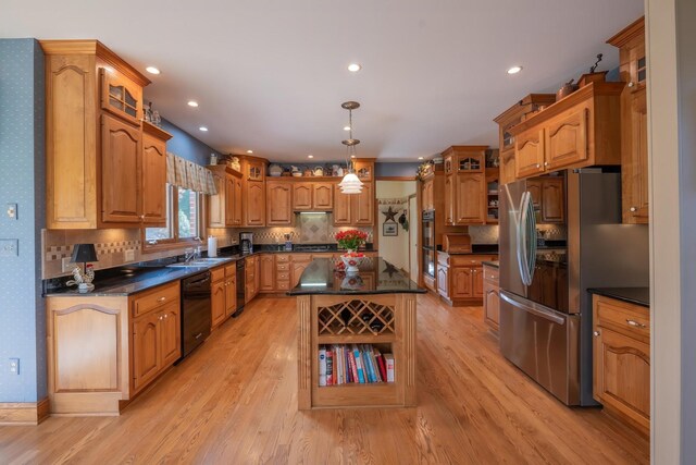 kitchen featuring a center island, black appliances, decorative backsplash, decorative light fixtures, and light wood-type flooring