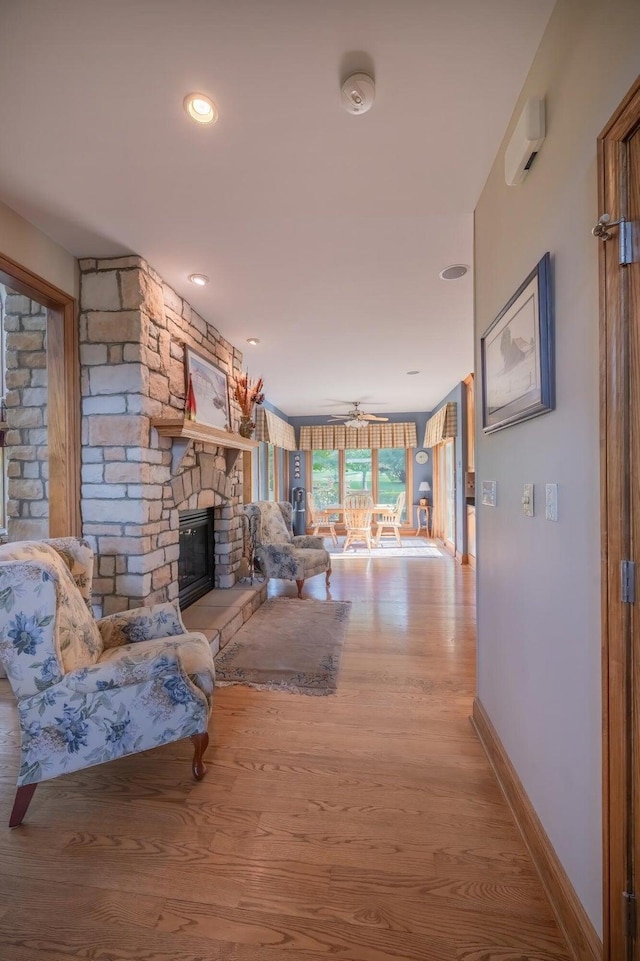 living room with a fireplace, light hardwood / wood-style floors, and ceiling fan