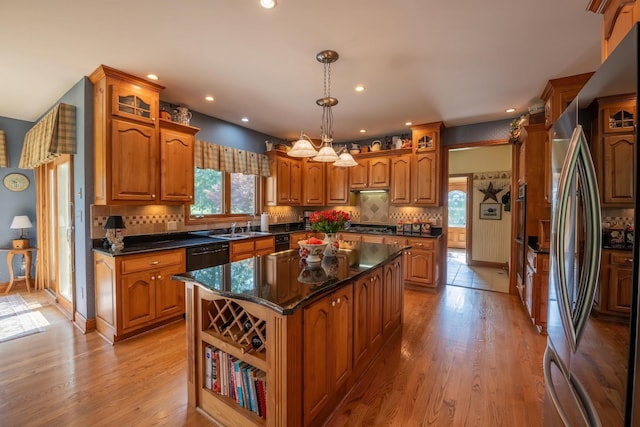 kitchen with pendant lighting, stainless steel refrigerator, dishwasher, decorative backsplash, and a center island