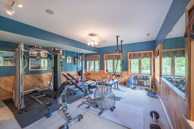 workout room featuring ceiling fan and wooden walls