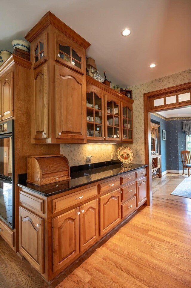 kitchen featuring black double oven, dark stone counters, and light hardwood / wood-style flooring