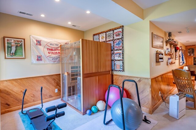 exercise room with light colored carpet and wood walls