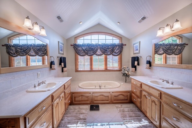 bathroom featuring lofted ceiling, a bath, vanity, and tile patterned floors