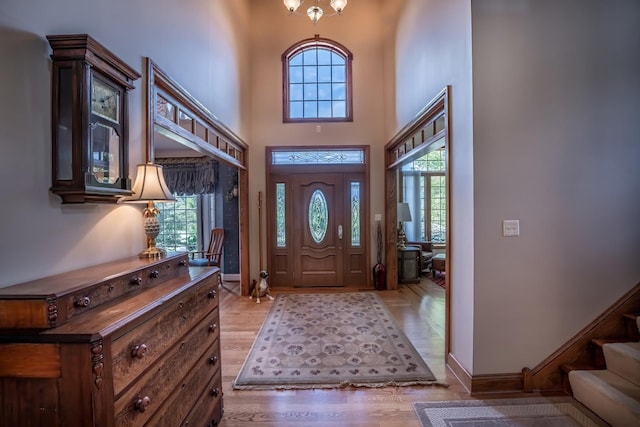 entrance foyer with a towering ceiling, an inviting chandelier, and light hardwood / wood-style floors