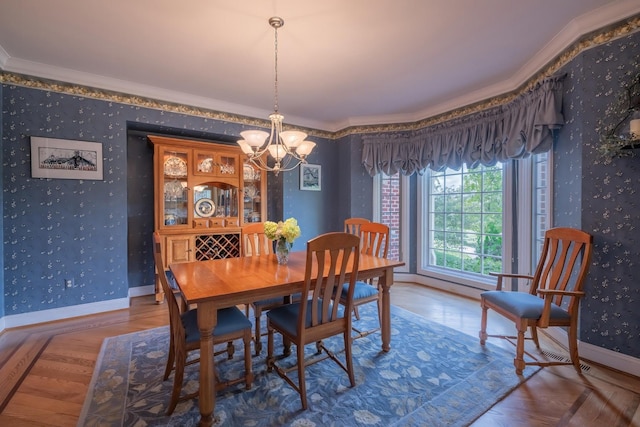 dining area with ornamental molding, parquet flooring, and an inviting chandelier