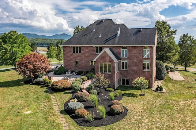 rear view of house featuring a yard, a mountain view, and a patio area