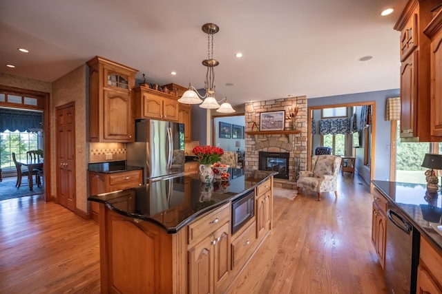 kitchen featuring dishwashing machine, stainless steel fridge, a stone fireplace, built in microwave, and decorative light fixtures