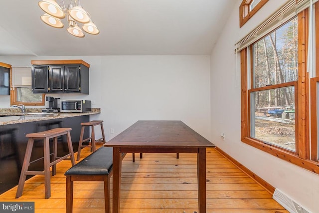 dining area featuring a notable chandelier, light hardwood / wood-style flooring, and sink