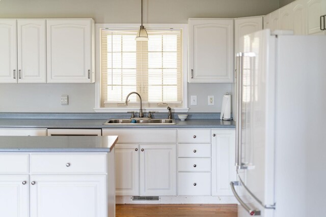 kitchen featuring pendant lighting, white cabinetry, sink, and white fridge