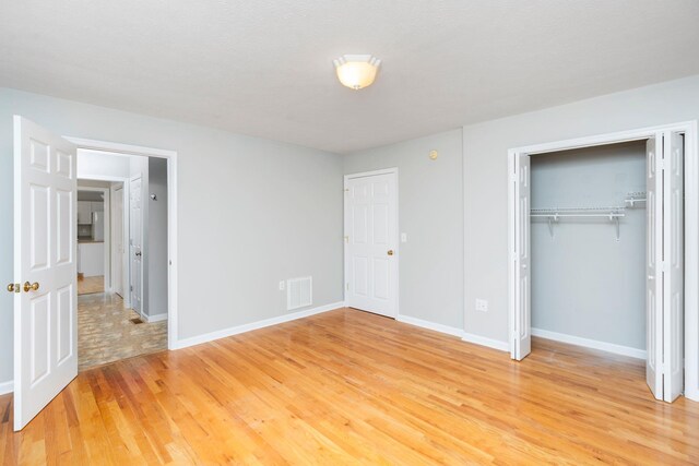 unfurnished bedroom featuring hardwood / wood-style floors and a closet