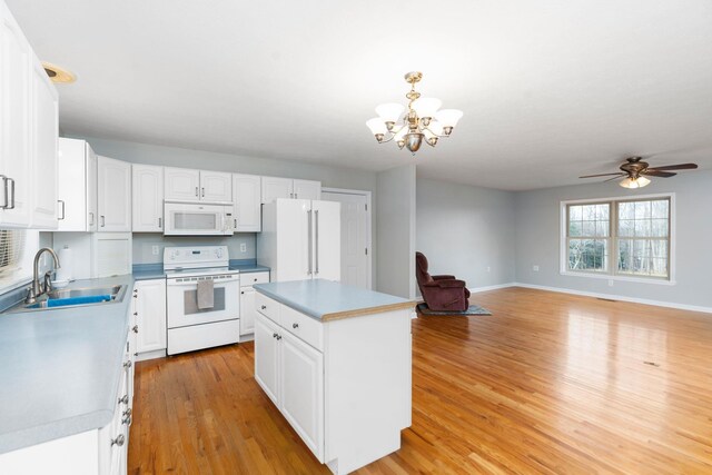 kitchen featuring sink, white appliances, a center island, white cabinets, and decorative light fixtures