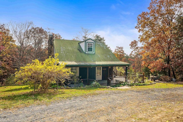 view of front facade featuring a porch, metal roof, and a chimney