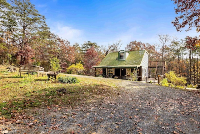 view of front of house featuring covered porch, a chimney, and metal roof