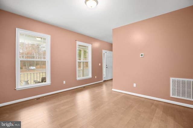 empty room featuring baseboards, visible vents, and wood finished floors