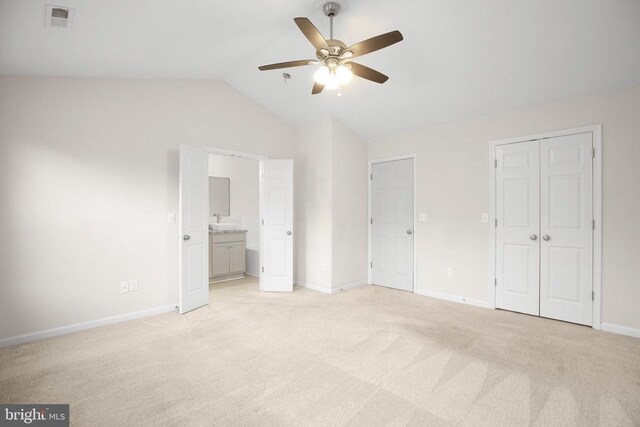 unfurnished bedroom with multiple closets, lofted ceiling, visible vents, light carpet, and baseboards