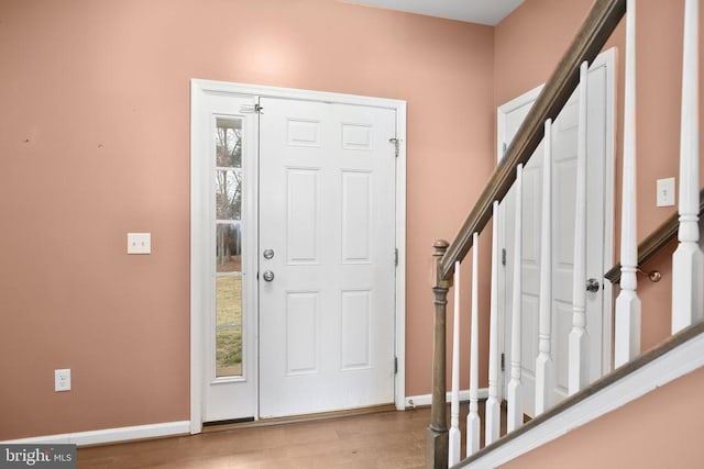 entrance foyer featuring stairway, baseboards, and wood finished floors