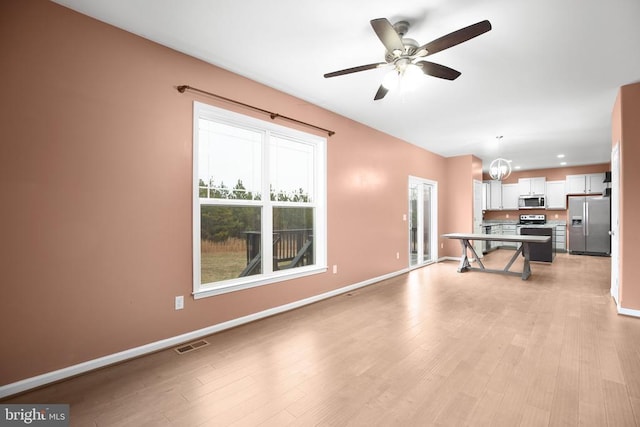 unfurnished living room featuring light wood-type flooring, baseboards, visible vents, and ceiling fan with notable chandelier