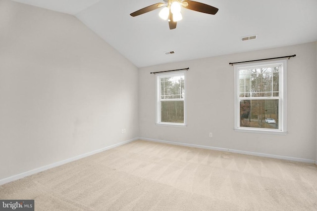 unfurnished room featuring light colored carpet, visible vents, vaulted ceiling, and baseboards