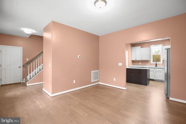 interior space featuring stairs, light wood-style flooring, visible vents, and baseboards