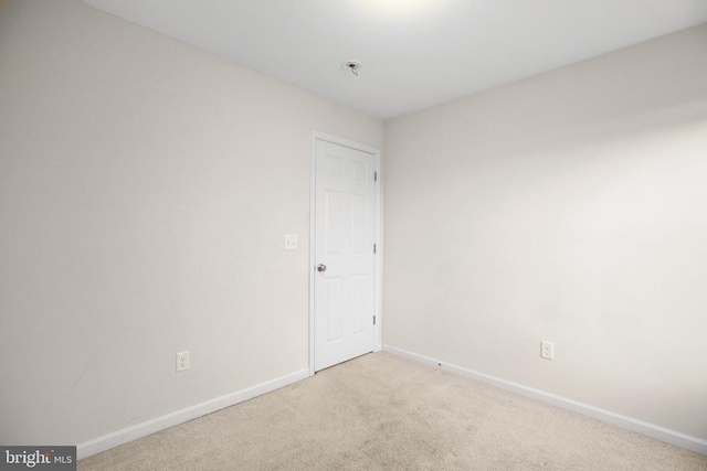 carpeted empty room featuring baseboards