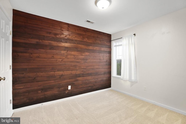 unfurnished room with baseboards, wooden walls, visible vents, and carpet flooring