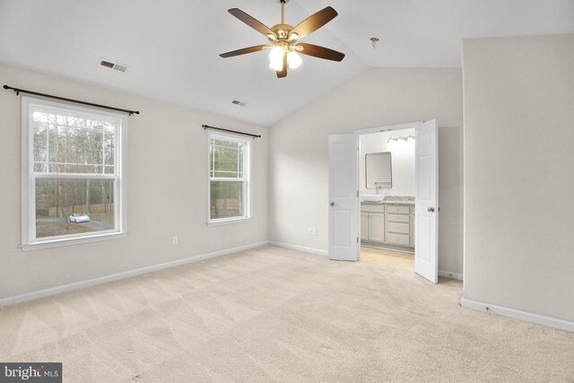 unfurnished bedroom with light colored carpet, visible vents, vaulted ceiling, and baseboards