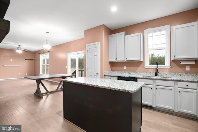 kitchen with a wealth of natural light, light wood-style flooring, a kitchen island, and a sink