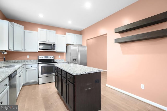 kitchen with a center island, light wood finished floors, open shelves, stainless steel appliances, and light stone countertops