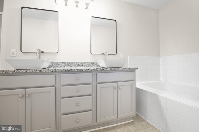 bathroom with tile patterned flooring, a sink, a bath, and double vanity