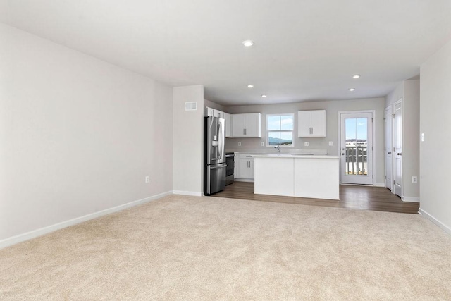 kitchen with sink, carpet floors, stainless steel appliances, and white cabinets