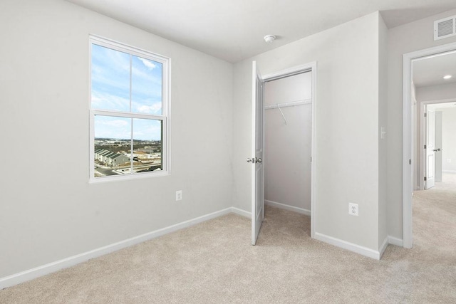 unfurnished bedroom with light colored carpet and a closet