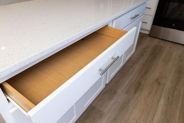 interior details featuring dark hardwood / wood-style floors, range, and white cabinets