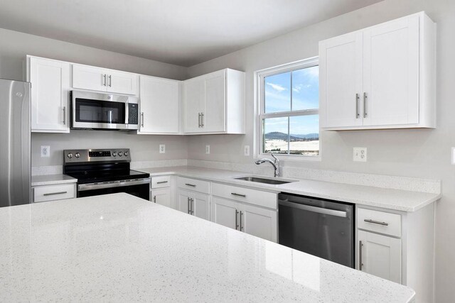 kitchen with light stone counters, sink, stainless steel appliances, and white cabinets