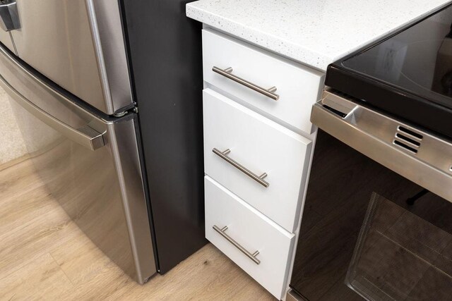 room details with electric range oven, stainless steel fridge, and light hardwood / wood-style flooring