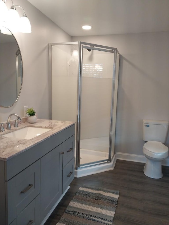 bathroom with vanity, hardwood / wood-style flooring, a shower with shower door, and toilet