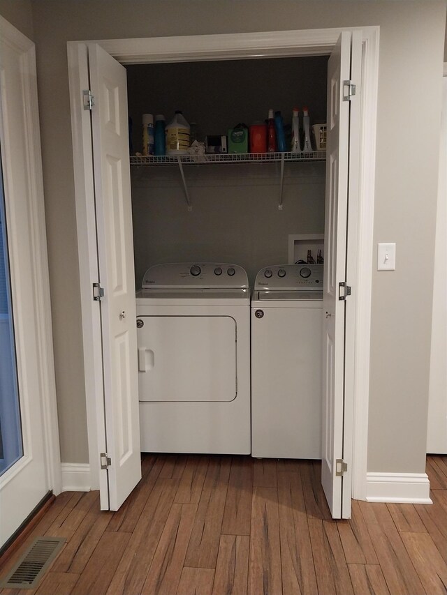 clothes washing area with washing machine and clothes dryer and light hardwood / wood-style floors