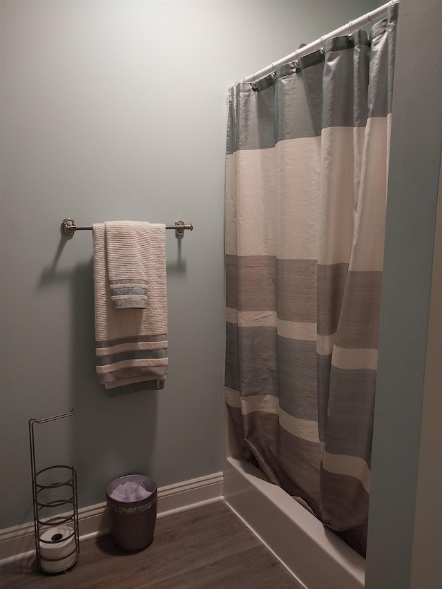 bathroom with shower / tub combo with curtain and wood-type flooring