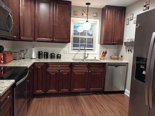 kitchen with sink, decorative light fixtures, stainless steel appliances, and light stone countertops