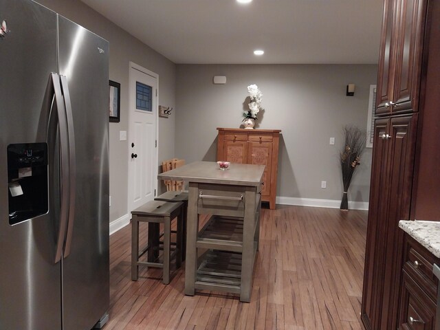 kitchen with stainless steel fridge, a center island, light hardwood / wood-style floors, and dark brown cabinets