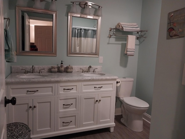 bathroom with walk in shower, vanity, toilet, and wood-type flooring