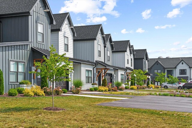 view of front of house featuring board and batten siding, a front yard, roof with shingles, a residential view, and uncovered parking