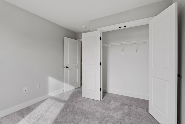 unfurnished bedroom with baseboards, carpet, and a closet
