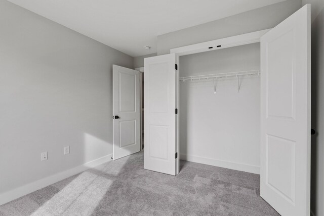 unfurnished bedroom with baseboards, carpet, and a closet