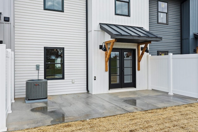 entrance to property featuring a standing seam roof, french doors, central AC unit, a patio area, and fence
