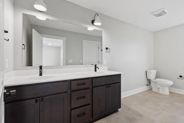 bathroom with double vanity, a sink, baseboards, and toilet