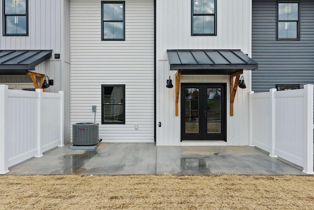 doorway to property with french doors, fence, a standing seam roof, and metal roof