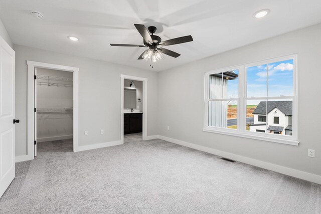 unfurnished bedroom with carpet flooring, recessed lighting, baseboards, and a walk in closet