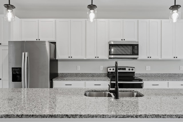 kitchen with white cabinetry, light stone countertops, appliances with stainless steel finishes, and hanging light fixtures