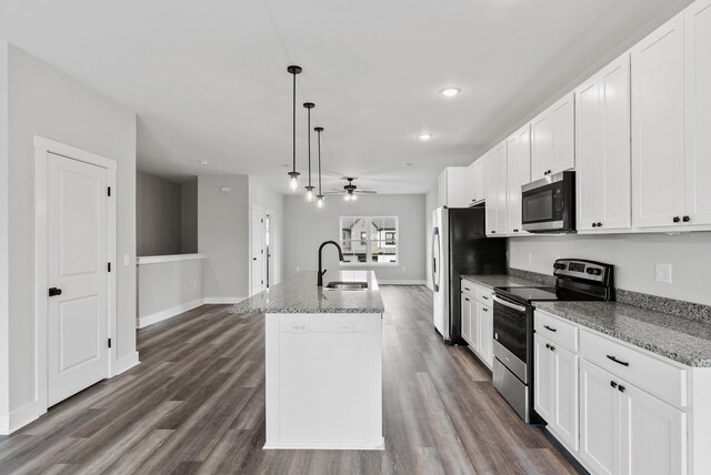 kitchen with ceiling fan, appliances with stainless steel finishes, a sink, a kitchen island with sink, and dark wood-style floors