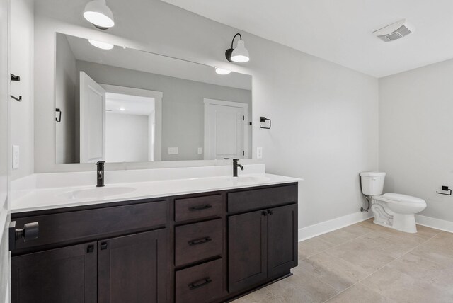bathroom featuring a sink, baseboards, toilet, and double vanity